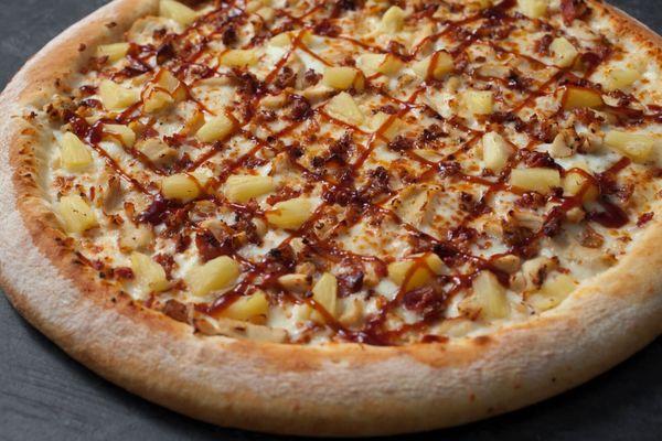 Barbeque Chicken Pizza, made with fresh dough, barbeque sauce, cheese, chicken, bacon, pineapple & drizzle of BBQ sauce on top