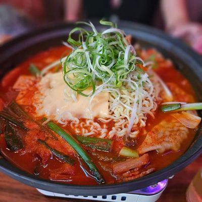 Army stew with ramen, tteokbokki, tofu, green onions, spam, bacon, and cheese. A bit too spicy and salty, but you can ask them to dilute.