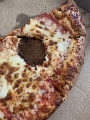 There's a literal burnt hole in the pizza. They packaged it up and delivered it anyway.