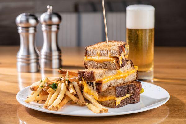 CORSAIR's Grilled Cheese features a rich blend of aged cheddar, gouda, and American cheeses on country bread, paired with crispy herb fries