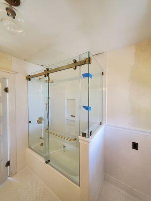 Our FLSD78DB sliding door kit with an extra glass panel at 90o return, beautiful setting 3/8" clear glass and satin brass hardware