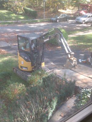 Edwards worker digging up the ground to replace the "orangeboard" with PVC (note the plywood laid down to protect the driveway)