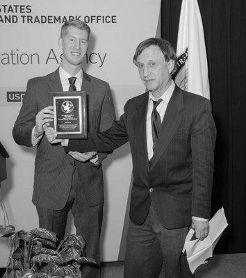 Photo of 2016 winner of Rossman Memorial Award in USPTO auditorium, Feb. 10, 2016. In my speech I read from Dr. Rossman's book (in my hand).