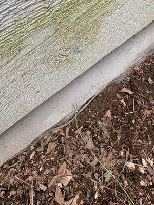 Shovel dirt up against the cedar siding