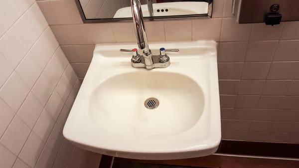 The sink in the men's restroom has a high pressure. Turn slowly or come out looking like you had a "accident" .