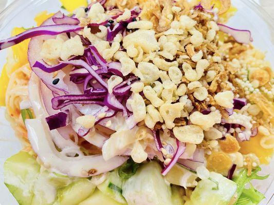 Kani salad with zoodles and greens filled with veggies, pineapple and mango