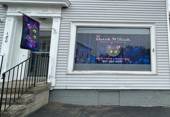 The storefront of Quick 'N Slick: our official mascot flag & window graphics with cosmic curtains as the background.