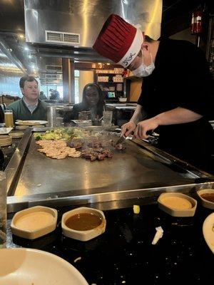 Chef at work slicing beef hibachi on the grill.