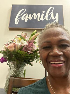 A beautiful smiling birthday girl with a beautiful floral arrangement of blush pink roses and lilies