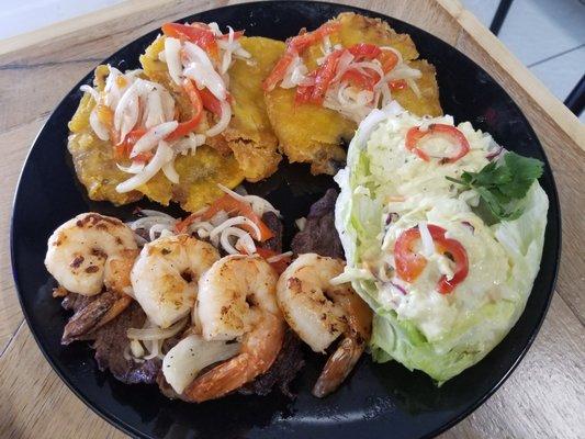 CAMARÓN EN CABALLO  A juicy strip of churrasco with 4 jumbo shrimp on top. Served with cole slaw and tostones.