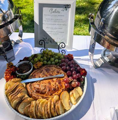 Baked Brie in Brioche: French Brie encased in homemade dough, garnished with bacon-fig jam, grapes, and served with semolina bread