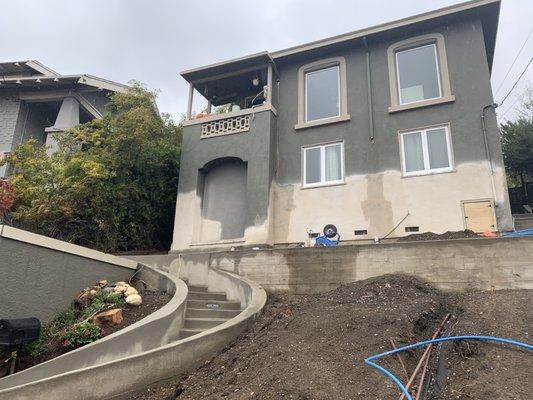 Foundation repair using drilled piers and grade beams.  Circular stair in front.