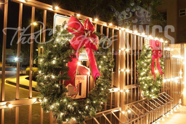 Gated entrance with lights, lit wreaths and bows.