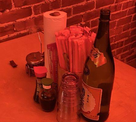 Table setting accompanied with water, water glasses, "Tatsu" sauce, 2 other Japanese sauces, chopsticks, forks, and paper towels.