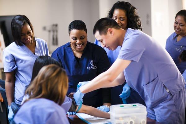 Students in the Bay Area Medical Academy 3-in-1 Medical Assistant Program practicing their phlebotomy skills