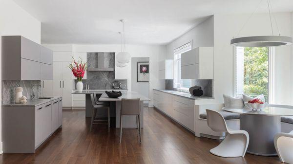 Unadorned flat panel doors create a soothing environment in light-reflecting glossy white on the perimeter, with soft matte gray on the bar