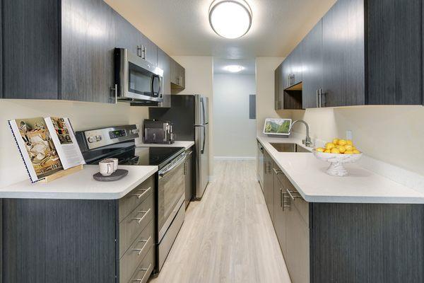 Modern kitchen with dark cabinetry, white granite countertops and stainless steel appliances.