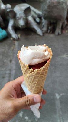 A scoop of blood orange and marrionberry in a waffle cone