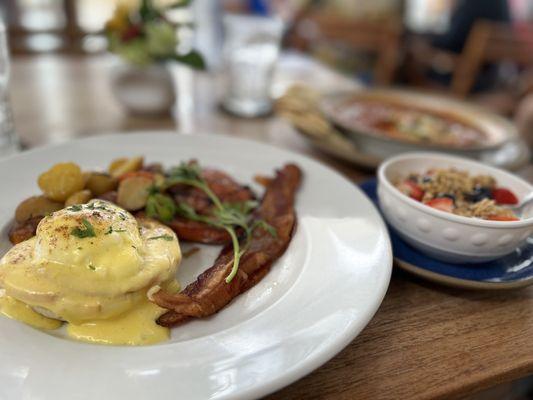 Chef's Special (Classic Eggs Benedict, Bacon, Roasted Potatoes, Portuguese Sausage) with a side of yogurt with granola and fresh berries