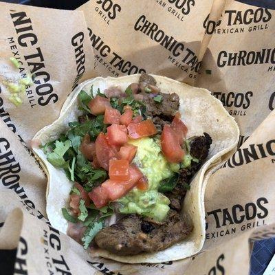 Steak taco with regrows beans guacamole tomatoes cilantro and lime