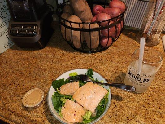 My salmon filet atop of my MIKOMI salad alongside their dressing & my lemonade within my souvenir glass BETHEL RD DISTILLERY