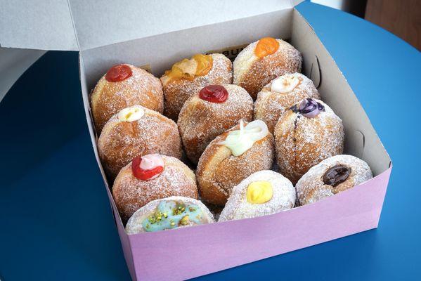 One Dozen Malasadas with a variety of fillings and sugar options.