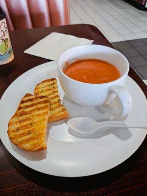 Tomato soup in a cup with garlic bread