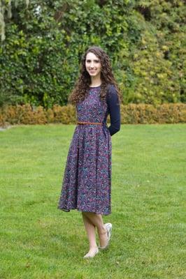 Floral sundress worn over a navy shell and belted with a tan woven belt