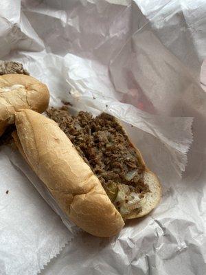 Nasty cheesesteak sandwich with raw veggies.