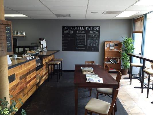 Inside view of front counter, bar seating, table and coffee flow chart .