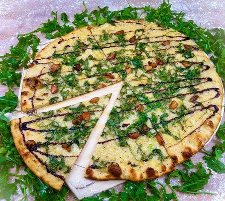 The Arugula pizza! A garlic oil base, topped with fresh arugula, mozzarella, fire roasted garlic, and a drizzle of sweet balsamic glaze.