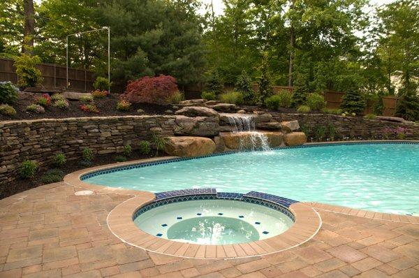 Gunite swimming pool with custom waterfall and fieldstone retaining walls.