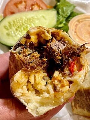 Barbacoa (choice of meat) burrito close up showing filling