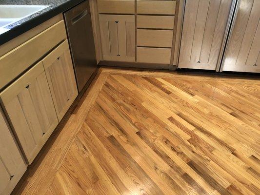 The finished product with new hardwood at base of the sink, dishwasher, and refrigerator.