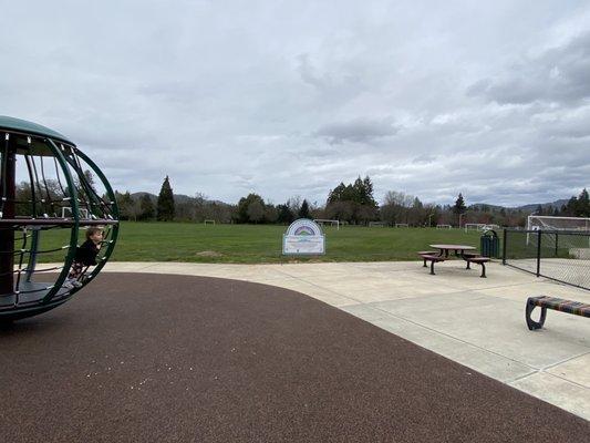 Behind the playground and grassy area with soccer goals, you'll find a tree-lined path that follows along the river.