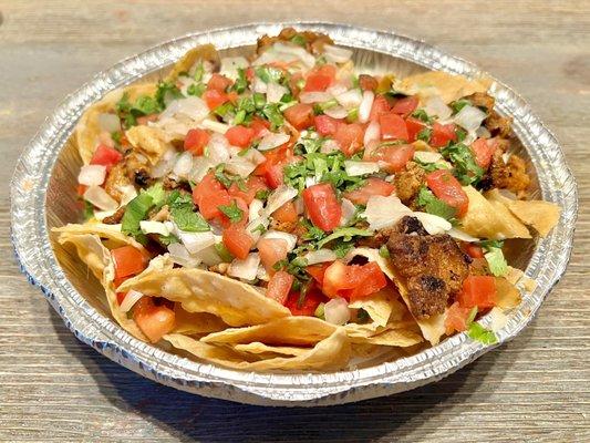 Nachos. Al pastor, refried beans, cheese, onion, and cilantro on top of crunchy tortilla chips.