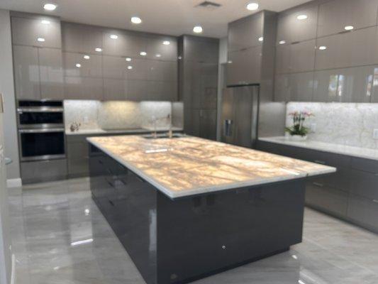 Elegant, sleek kitchen. Island counter is a single slab of translucent Cristallo highlighted by under counter lighting !!