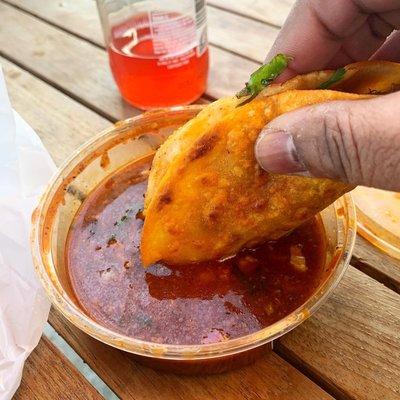 Dipping taco into birria consommé