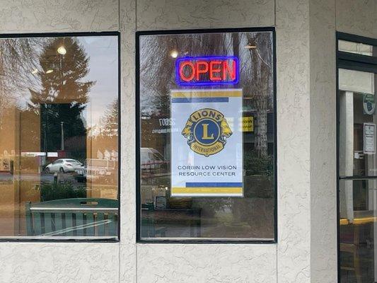 front window of building with open sign and Lions low vision sign