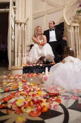 Bride and Groom on stair case with Flower petals and little girl