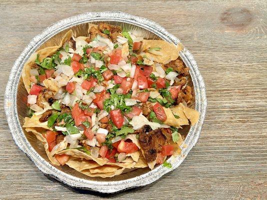 Nachos. Al pastor, refried beans, cheese, onion, and cilantro on top of crunchy tortilla chips.