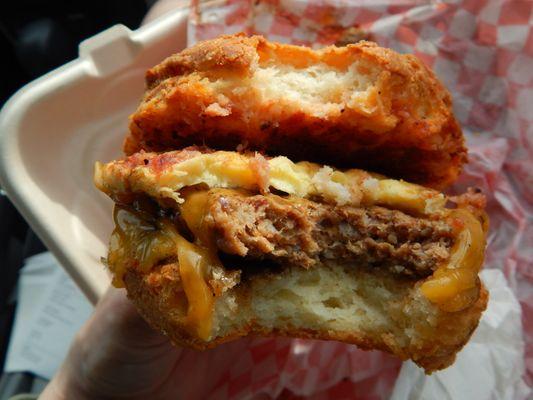 Lumberjack sandwich with buttermilk biscuit, cheese, sausage patty, egg, and a red sauce of sorts.