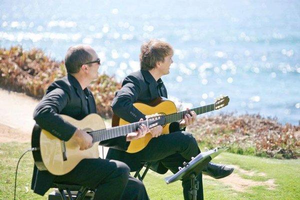 Playing as a guitar duo for a seaside wedding ceremony.