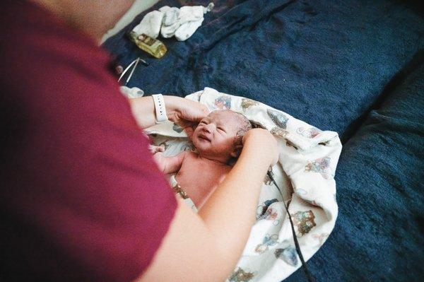 Midwife Charlee conducting Otis' newborn exam after he was born at home!