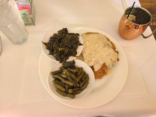 Country fried steak with a side of green beans and a side of collards.