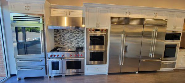 kitchen showroom with stainless steel appliances on display and white cabinetry