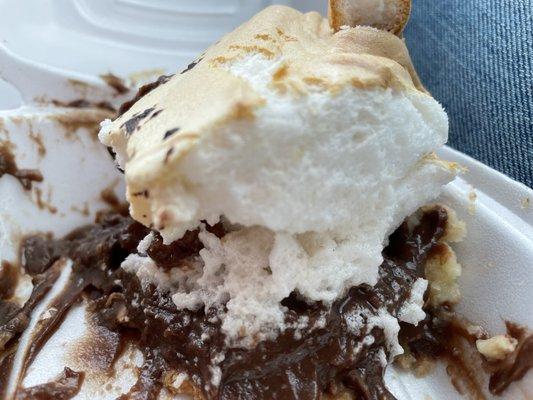 Half eaten chocolate crème pie with merengue topping.