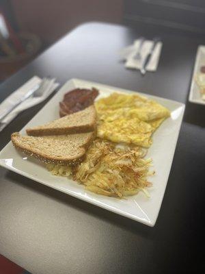 Scrambled (hard) eggs, crispy bacon, hashbrown and wheat toast