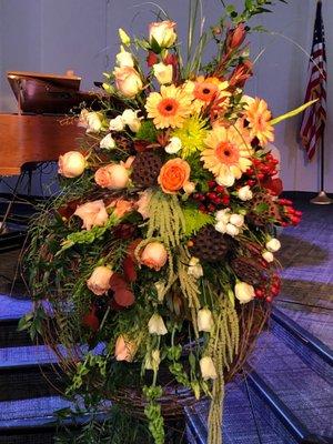 Grapevine wreath with peach rosebuds, coral gerbera daisies, green spider mums, mini white roses, etc.