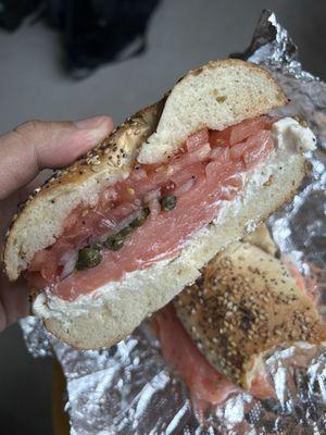 Lox, cream cheese, onions, tomato, and capers on a toasted everything bagel